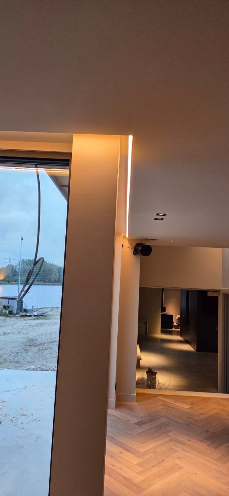 Afgewerkte architecturale verlichting met LED-strip, inbouwspots en visgraatvloer in een moderne woning