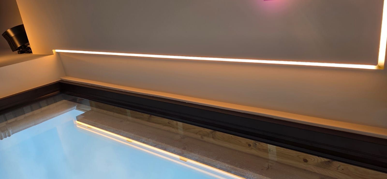 Afgewerkte verzonken warme LED-strip in een strakke wand, met reflectie in een wateroppervlak
